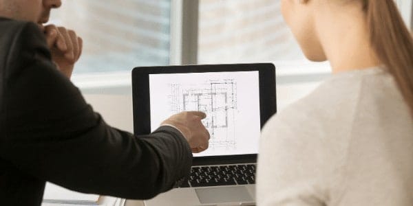 A designer sits with client and reviews home design plans