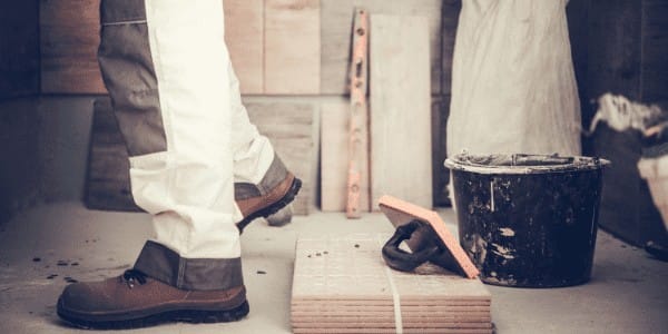 A tiler stands in an unfinished bathroom remodel.