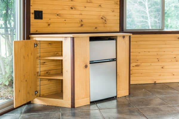 Cabinet with storage and a mini fridge in a gazebo remodel by Spears Design Build Group.