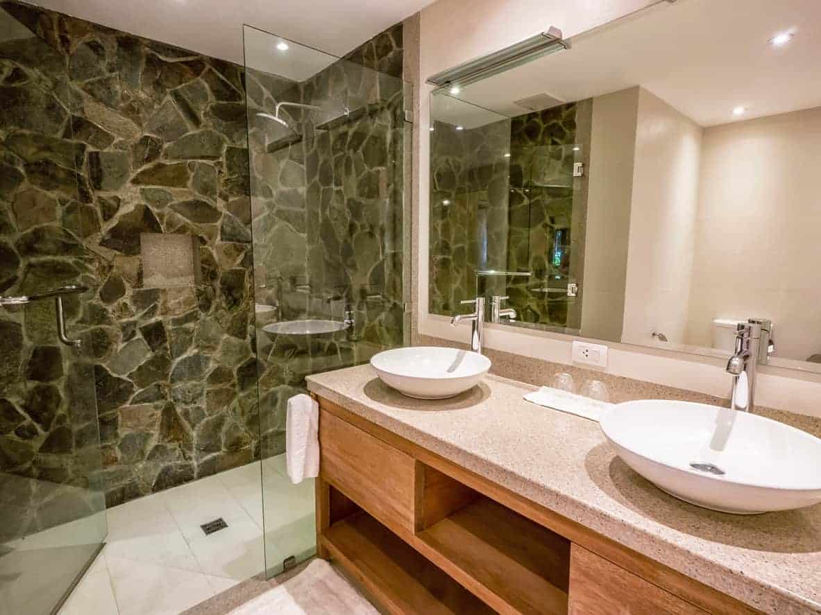 Modern bathroom with stone wall and double sinks.
