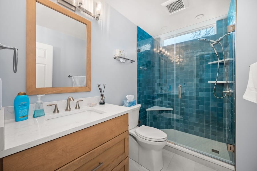 Guest hallway bathroom makeover showing off new vanity, toilet, and shower with new blue tile.